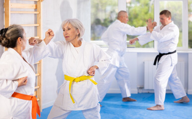 Two elderly women in kimono practice painful blows during karate lessons © JackF