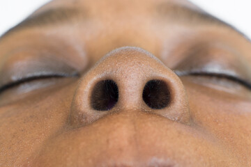 Brown skin woman with a button nose and round nostrils, selective focus on a small nose, black...