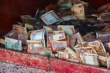 Ayodhya, India. Close up view of indian banknotes and coins in donation box.