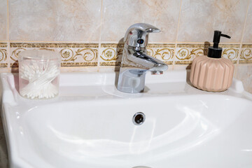 Plain white sink with faucet and liquid soap in the bathroom