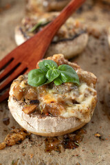 Stuffed mushrooms with melted cheese, vegetables, and spices on baking sheet with wooden fork. Close-up. Selective focus. Healthy vegetarian appetizer or party food.