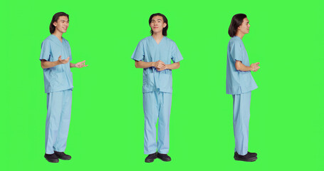 Cheerful nurse waving in studio and greeting sick people, standing over full body greenscreen backdrop. Medical specialist assistant being respectful and friendly with patients, healthcare uniform.