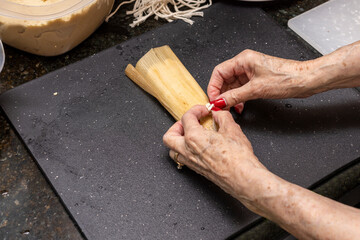 Beef red chili Tamales being made assembled  by hand on a kitchen counter top.