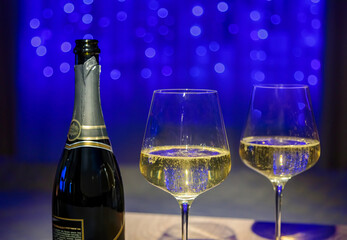 Champagne glasses and bottle on garland background, festive mood