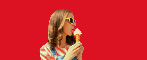 Summer portrait of happy young woman eating ice cream wearing sunglasses on red studio background