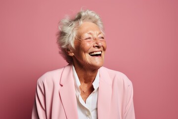 Portrait of a happy senior woman laughing isolated over pink background.