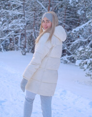 Fototapeta na wymiar A woman in a white jacket and hat standing in the snow