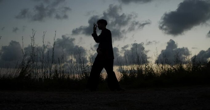 Silhouette of man practicing chi kung during a spectacular sunset in nature