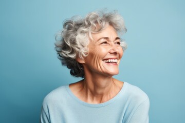 Portrait of a happy senior woman smiling and looking up on blue background