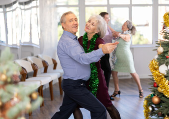 Couple of elderly man and elderly woman dancing tango in studio