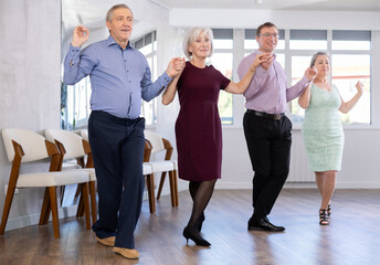 Elderly people with middle-aged man holding hands dancing hava nagila. Dance lessons for amateurs...