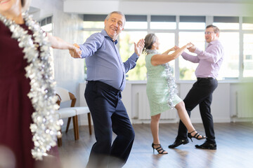 At New Years party for studio students, elderly couple performs lindy hop dance. Beginners and amateurs learn their favorite deal and dance classes