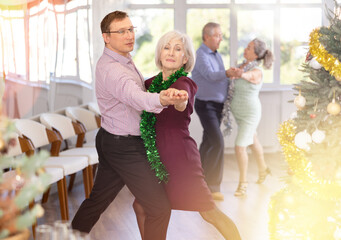 Aged couple during celebration Christmas and New Year dancing cha-cha-cha dance at modern ballroom