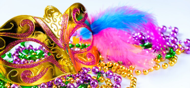 Golden carnival mask and colorful beads on white background. Closeup symbol of Mardi Gras or Fat Tuesday.