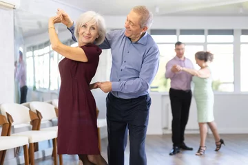 Deurstickers Happy mature woman enjoying impassioned merengue with male partner in latin dance class. Social dancing concept © JackF