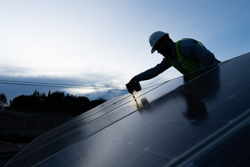 silhouette of an engineer installing and giving maintenance to solar panels, concept of renewable energy power, professional technician working on a roof with blue sky background