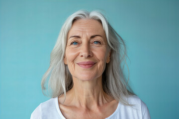 
beautiful elderly woman , blue eyed model with beautiful gray hair smiling in the studio isolated on pastel blue background