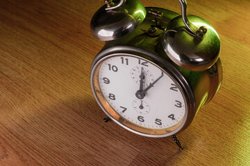 Old metallic table clock. Illuminated with colorful lights on a wooden floor. Time concept image....