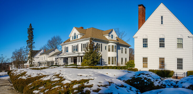 Historic district street winter landscape with landmark colonial houses and gardens covered with snow in New England, United States