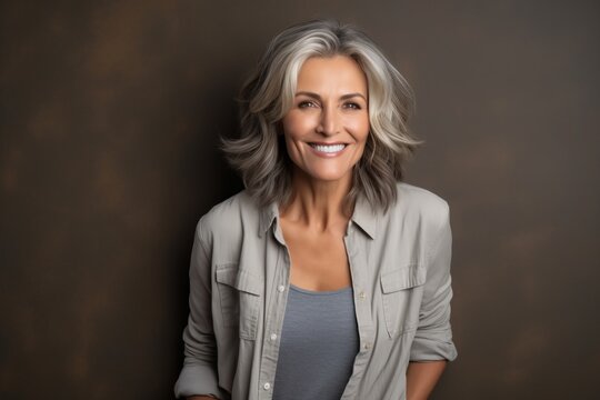 Portrait of a beautiful middle-aged woman with grey hair smiling and looking at the camera.