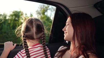 little girl her mother look out car window. happy family. mother daughter child girl kid back seat...