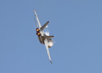 F-18 Hornet in a high G maneuver in beautiful light, with condensation streaks at the  at the wing...