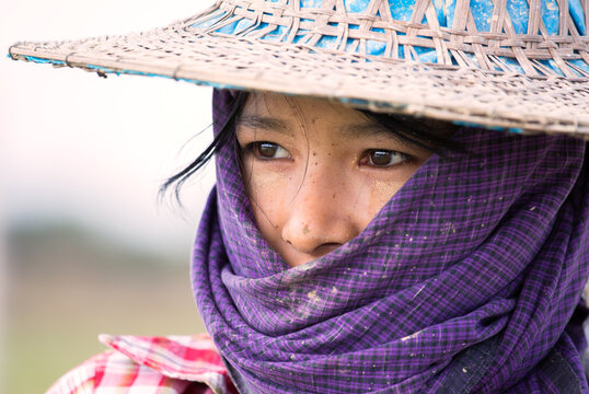 Portrait of young woman with scarf working in a rice field, Myanmar