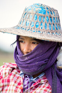 Portrait of young woman with scarf working in a rice field, Myanmar