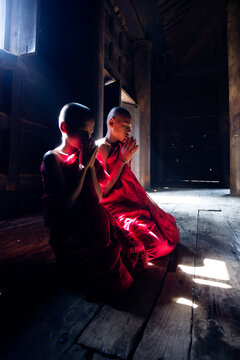 Two buddhist novice monks praying inside a monastery. Myanmar