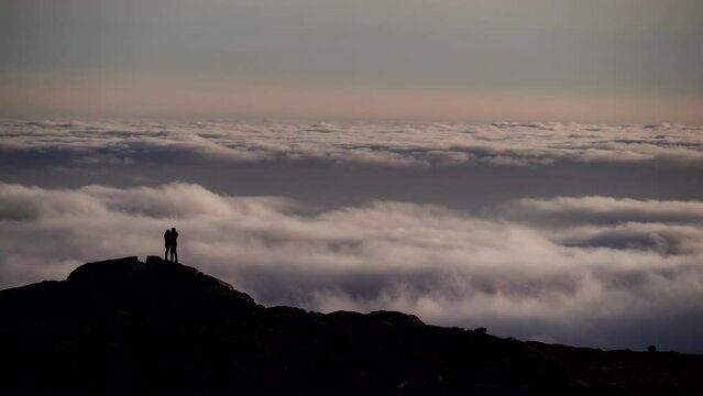 Silhouette of two people making selfie photo in mountain above clouds. Travel, holidays picture.