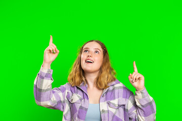 Young woman showing thumbs up and pointing empty place over head, advertising area for commercial text, copy space for goods promotion advertisement. Girl isolated on chroma key background. Lifestyles