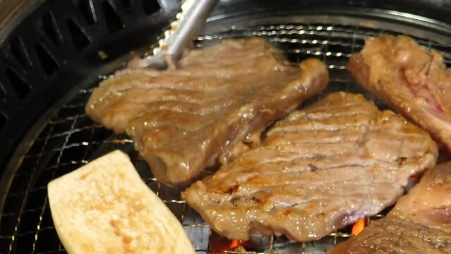 수제 양념 돼지갈비를 숯불에 지글지글 맛있게 구워 쌈장을 찍고 상추쌈을 싸먹는 모습
