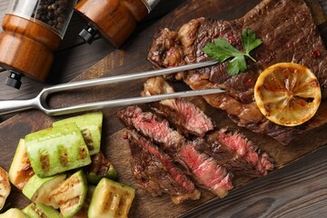 Delicious grilled beef steak and vegetables served on wooden table, top view