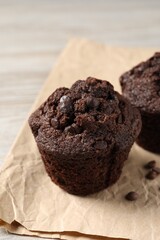 Delicious chocolate muffins on light wooden table