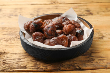 Roasted edible sweet chestnuts in bowl on wooden table