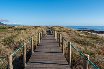 Fototapeta na wymiar Wooden walkway on the dune of Carreço beach with silhouette in the background, Viana do Castelo PORTUGAL