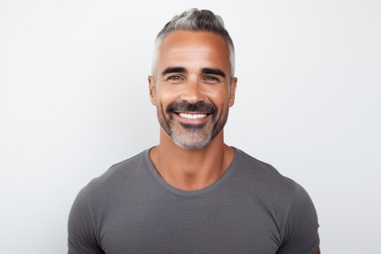 Portrait of handsome mature man smiling and looking at camera against grey background