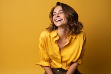 Portrait of a happy young woman laughing and looking up over yellow background