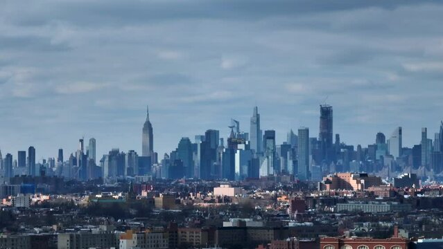 An aerial view of the east side of New York City from over Flushing Meadows Corona Park in Queens on a cloudy day. The camera boom down in front of apartment buildings with the city in the background.
