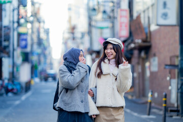 woman girl tourist Two Asian friends but different religions, one of whom is a Muslim girl. Walking tour of the city, city view, traveling in Japan Tokyo. with fun She is traveling in the city area.