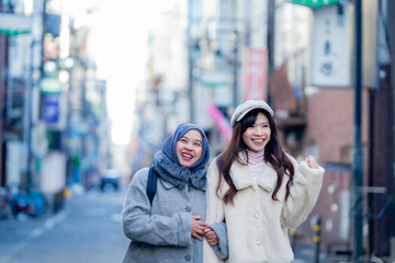 woman girl tourist Two Asian friends but different religions, one of whom is a Muslim girl. Walking tour of the city, city view, traveling in Japan Tokyo. with fun She is traveling in the city area.
