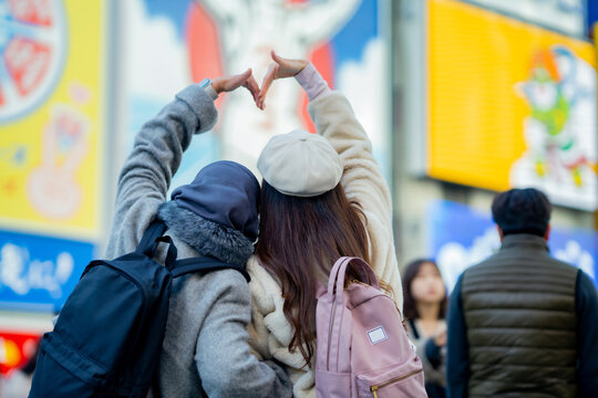 woman girl tourist Two Asian friends but different religions, one of whom is a Muslim girl. walking traveller shopping street food at Dotonbori or dotombori Shinsaibashi, Osaka City, Osaka, Japan.