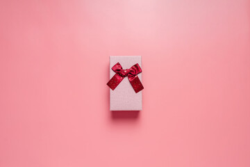 Top view photo of valentine's day decorations giftbox with silk ribbon bow on isolated pastel pink...