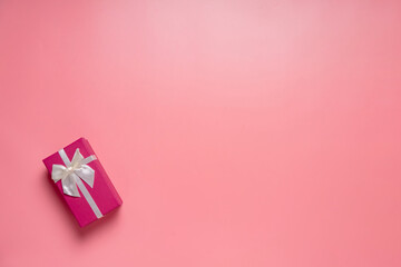 Top view photo of valentine's day decorations giftbox with silk ribbon bow on isolated pastel pink background with copyspace, concept Valentine's Day.