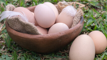 Organic brown and white eggs piled in a basket in the green grass