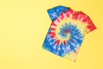 Blue-yellow-red tie dye T-shirt on a yellow background.