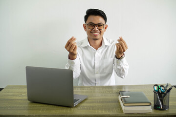 young asian businessman in a workplace making money gesture, wearing white shirt with glasses isolated