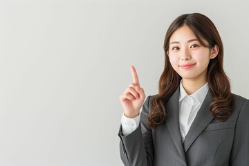 指をさす日本人の女性ビジネスマンウーマンのポートレート写真（白背景・会社員・スーツ・若手・OL・新入社員・窓口・案内）