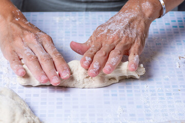 Woman's hands making rolls with the dough.