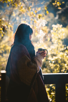 Mujer disfrutando de una taza de caf&eacute; en un clima fr&iacute;o en el bosque